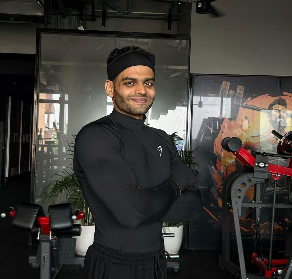 Coach Amritangshu Mahapatra in the gym, arms crossed and smiling